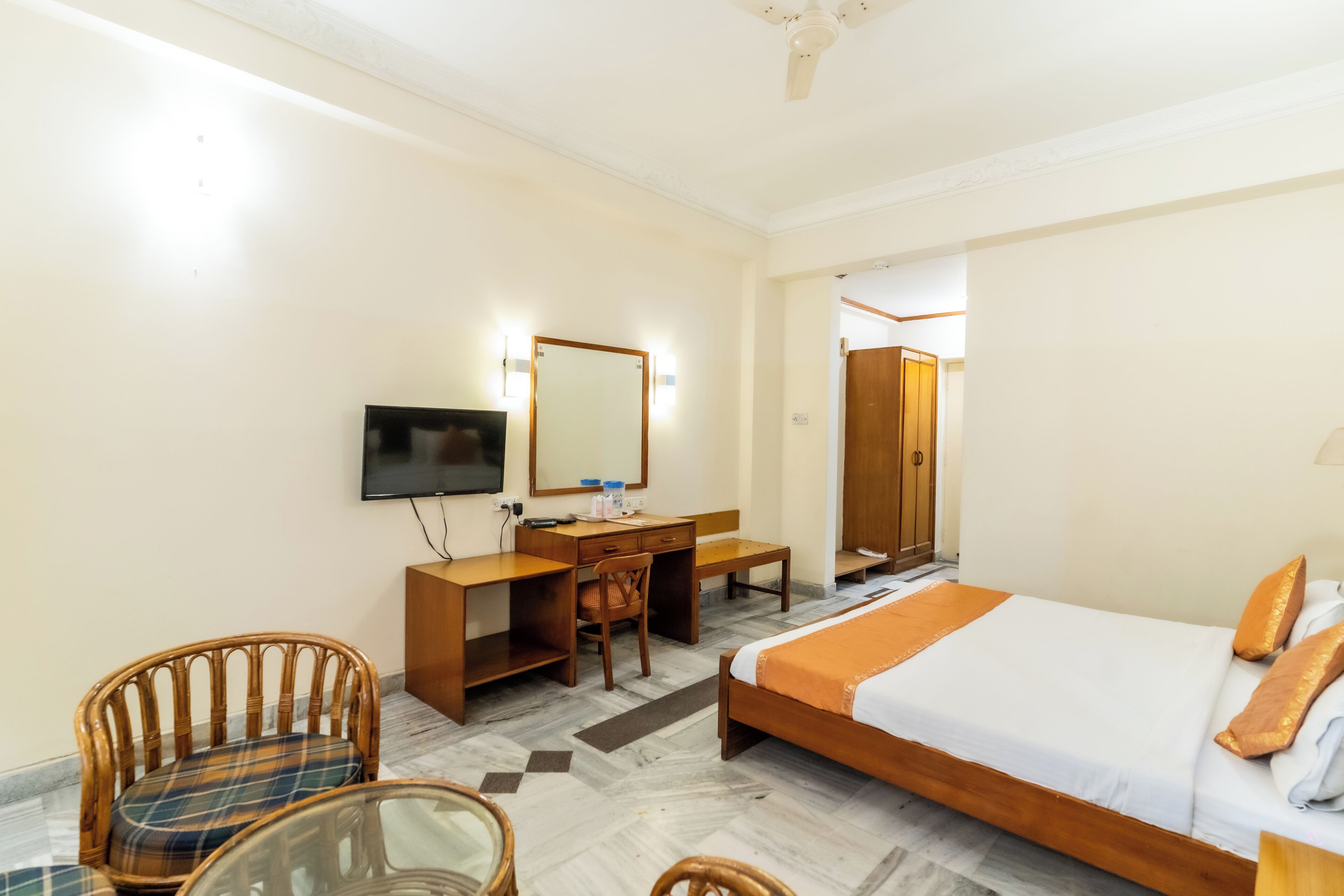 A hotel room with a bed, desk, chair, television, and a mirror.