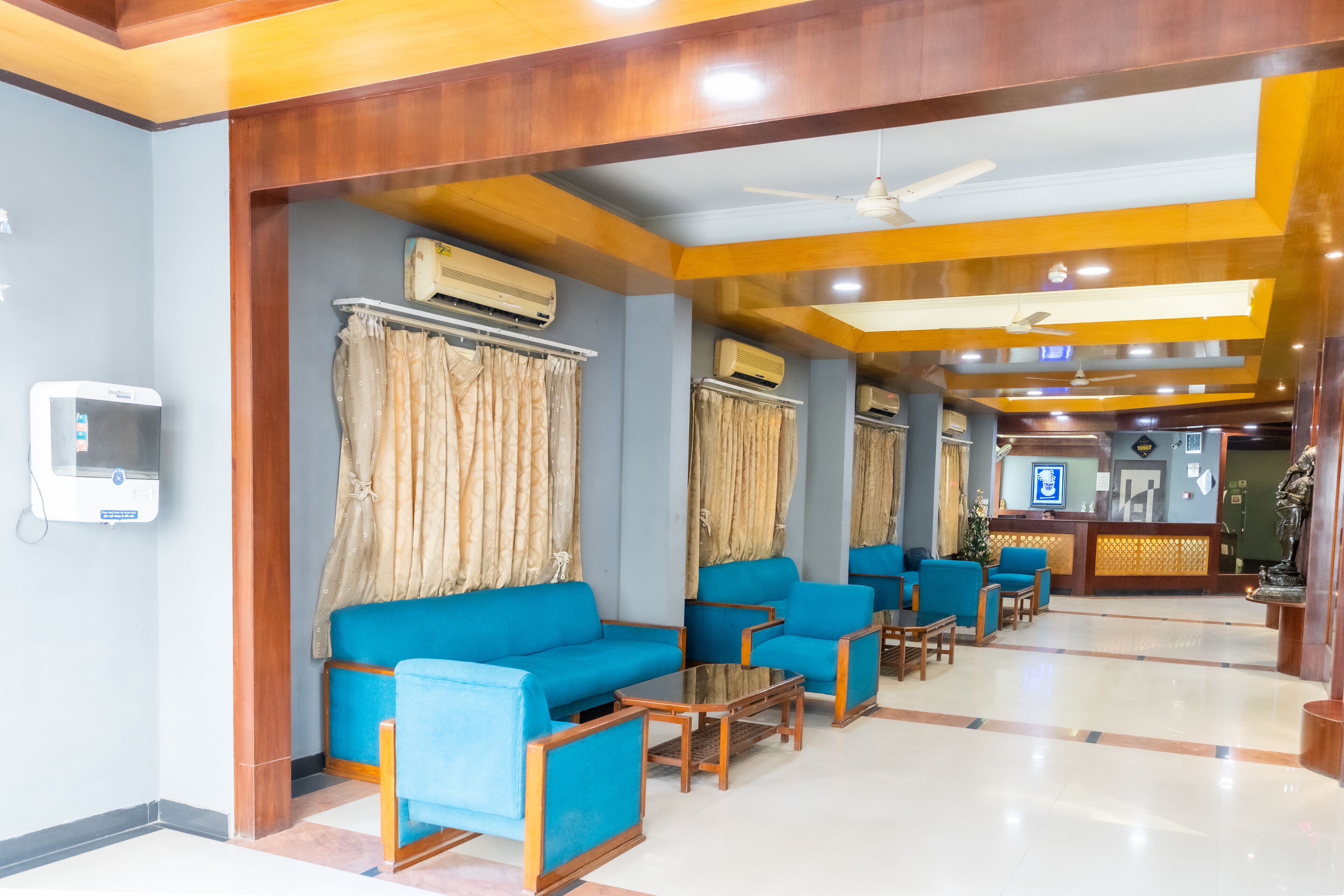 Un hall de hotel con sofás y sillones azules, y una recepción.