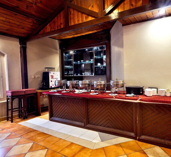 Una cocina con una isla de madera, una cafetera y un ventanal con cristalería.