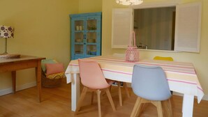 A dining area with a table, chairs, a basket, a cabinet, and a hanging light fixture.