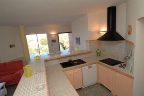Modern kitchen with double sink, oven, and range hood, complemented by a bright backsplash and light cabinetry.