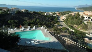 Zona de piscina con sillones de descanso y vista al mar.
