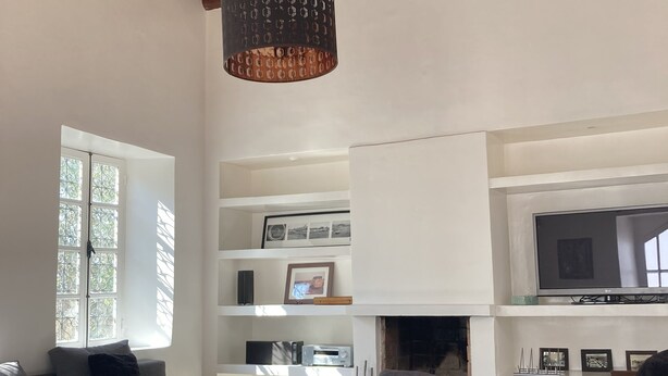 A spacious living room with a high wooden ceiling, a fireplace, and a television.