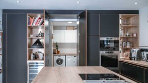 A modern kitchen with a central island, built-in appliances, and open shelving.