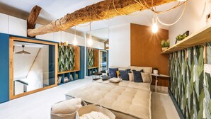 A modern bedroom with a large bed, a wooden ceiling beam, and a mirrored wardrobe.