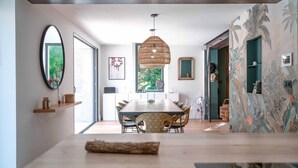 A modern dining area with a wooden table, wicker chairs, and a hanging light fixture.