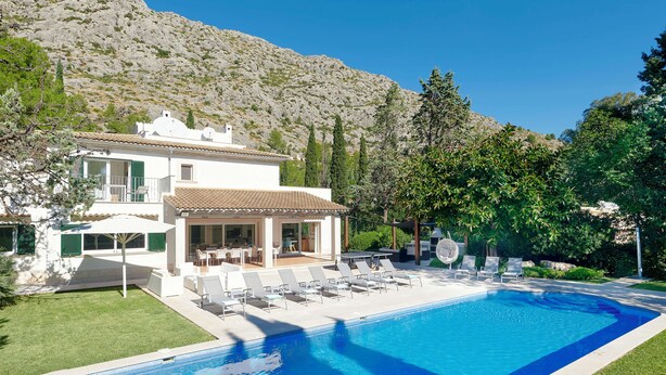 Een moderne villa met een zwembad, terras en een berg op de achtergrond.