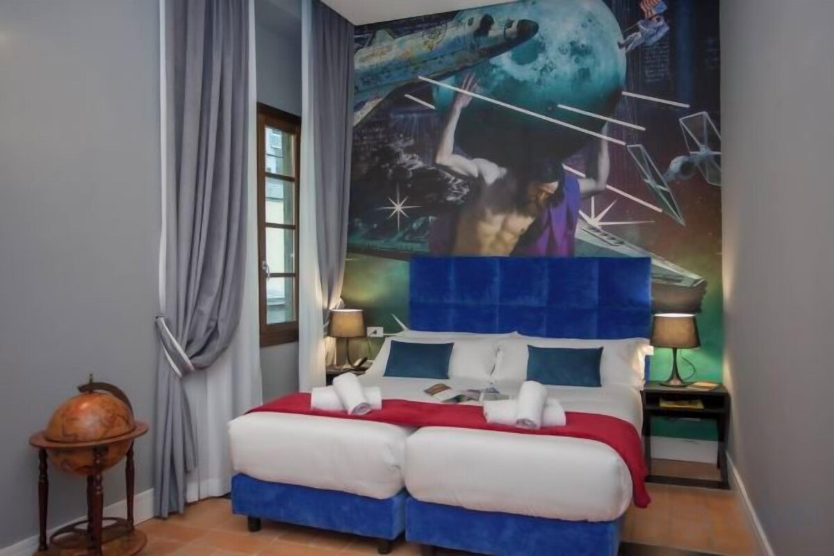 A double bed with a blue headboard, a globe on a side table, and a wall mural.