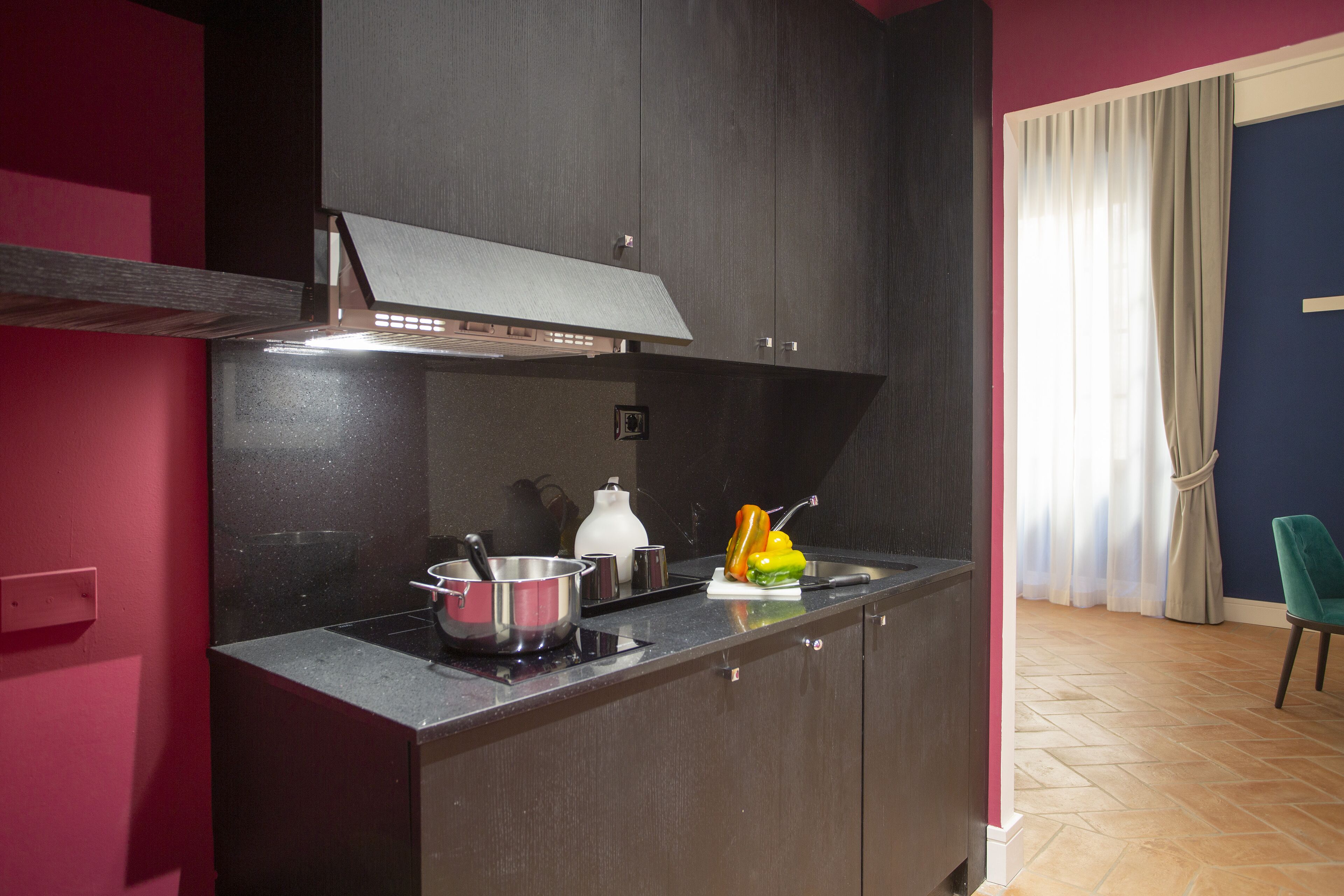 A kitchen with dark cabinets, a countertop, and a window with curtains.