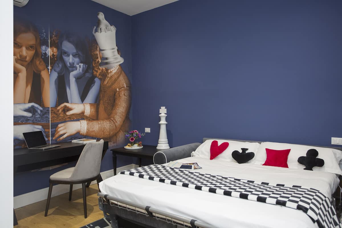 Un dormitorio con una cama, un escritorio, una silla y un cuadro grande en la pared.