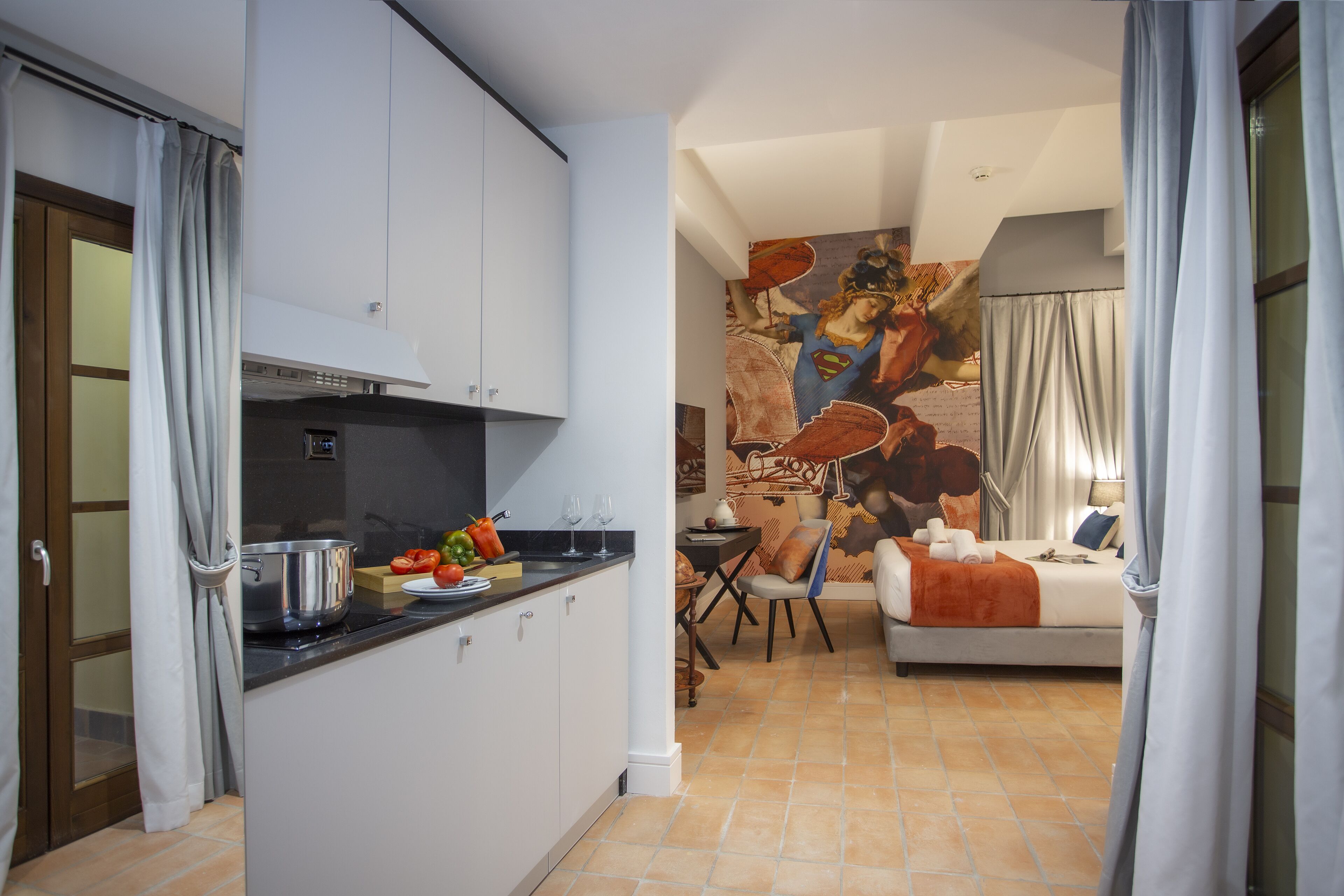 A modern kitchen with a dining area, a sofa, and a large mural.