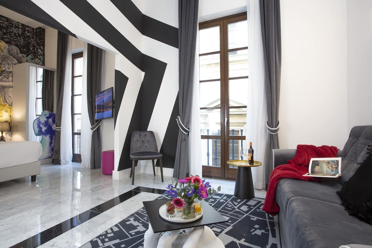 Una sala de estar moderna con un sofá, una mesa de centro con flores, un televisor y vistas al exterior.
