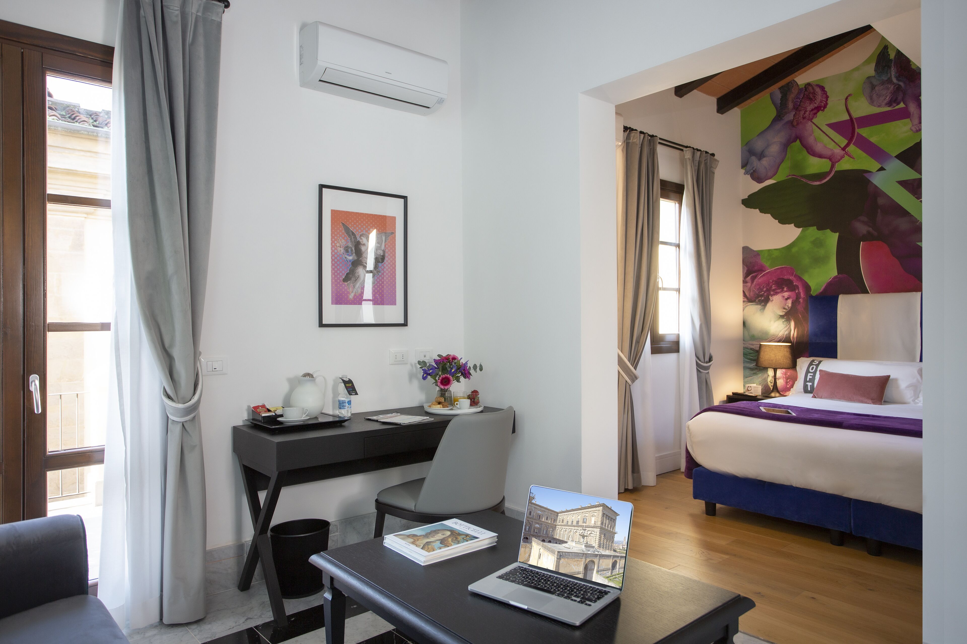 Habitación de hotel con cama, escritorio, silla y una computadora portátil.