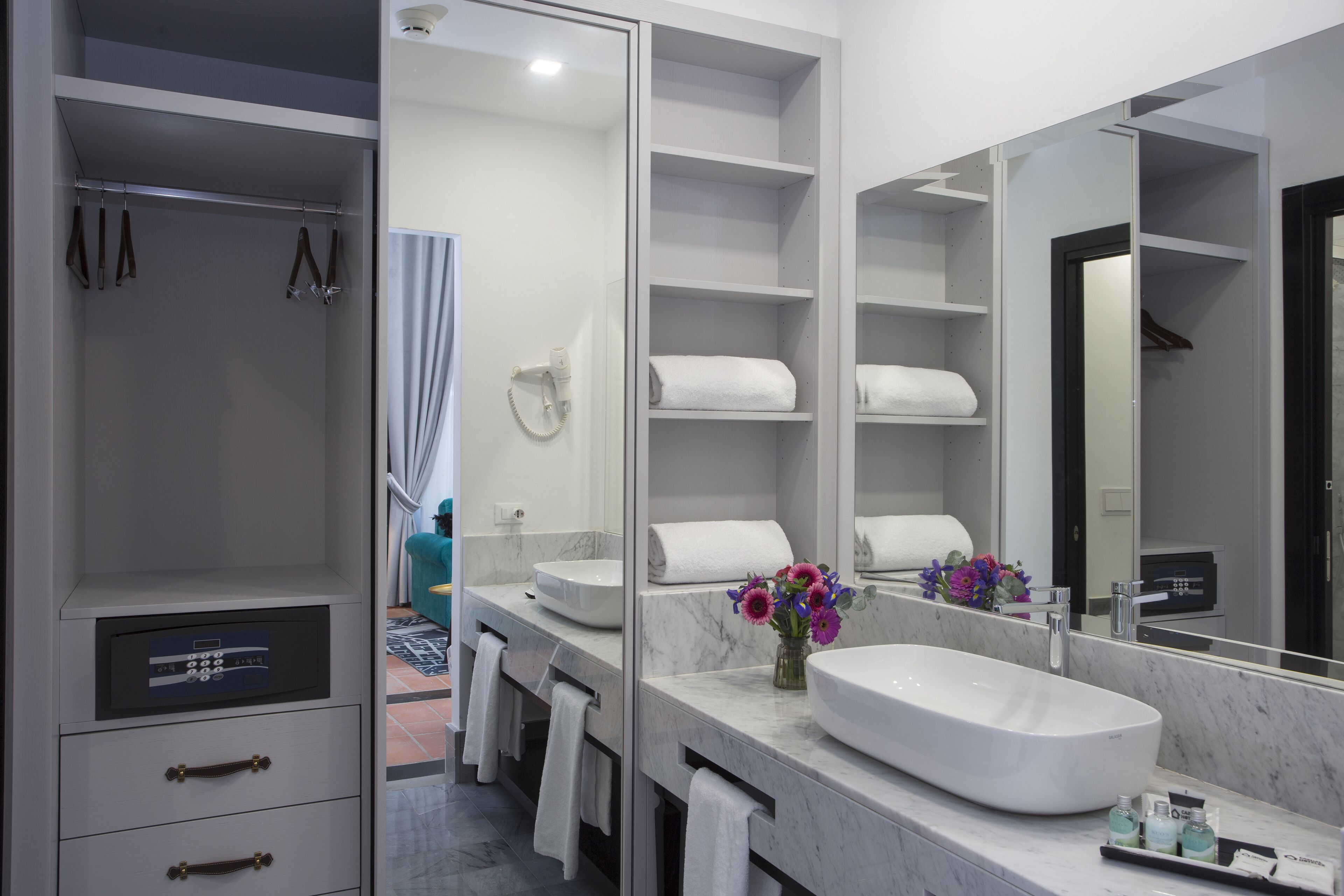 A modern bathroom with a large mirror, white sink, and built-in shelves.