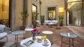 Une cour avec des espaces de détente en plein air, des plantes en pot et un coin aménagé pour le petit-déjeuner.