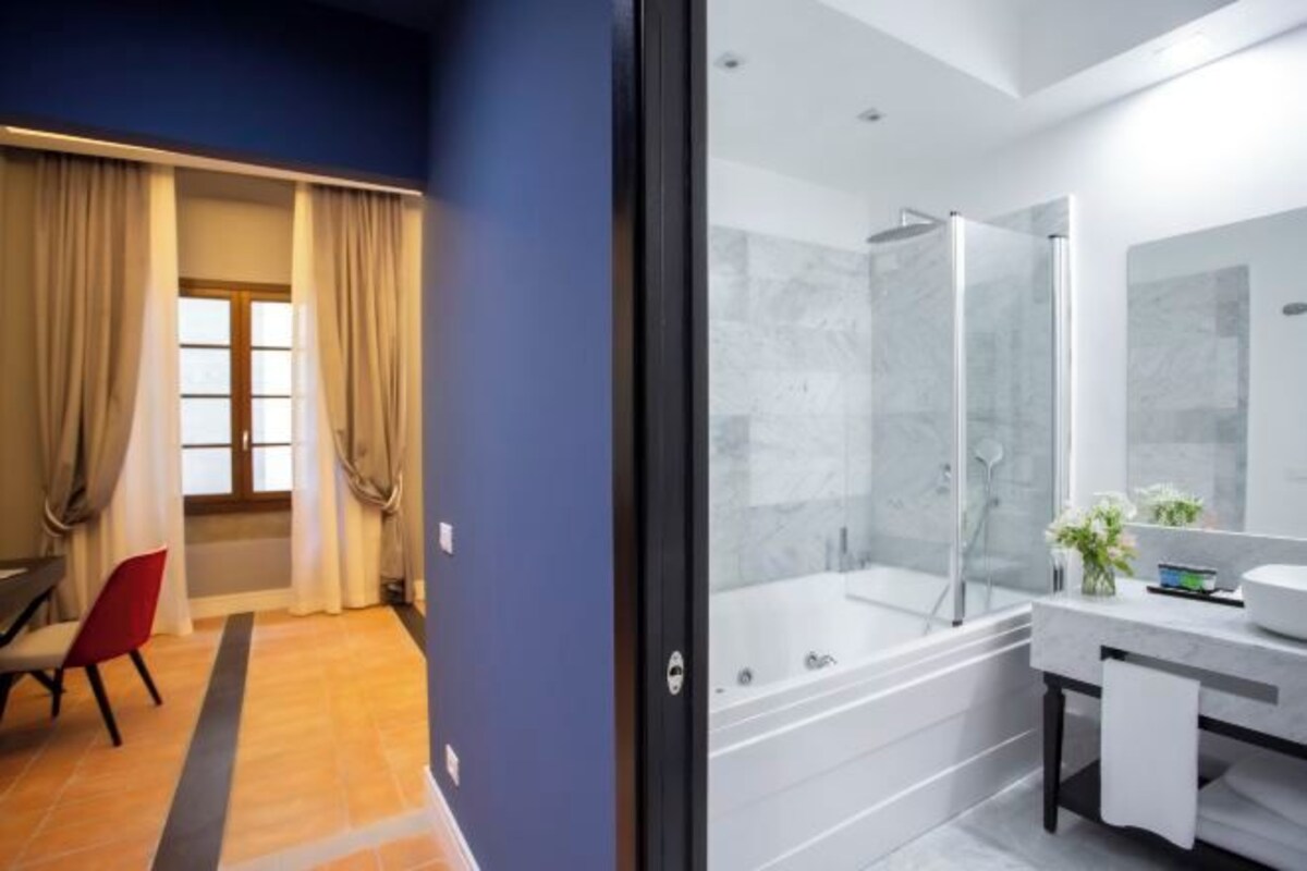 A modern bathroom with a glass-enclosed shower, a large mirror, and a bathtub.