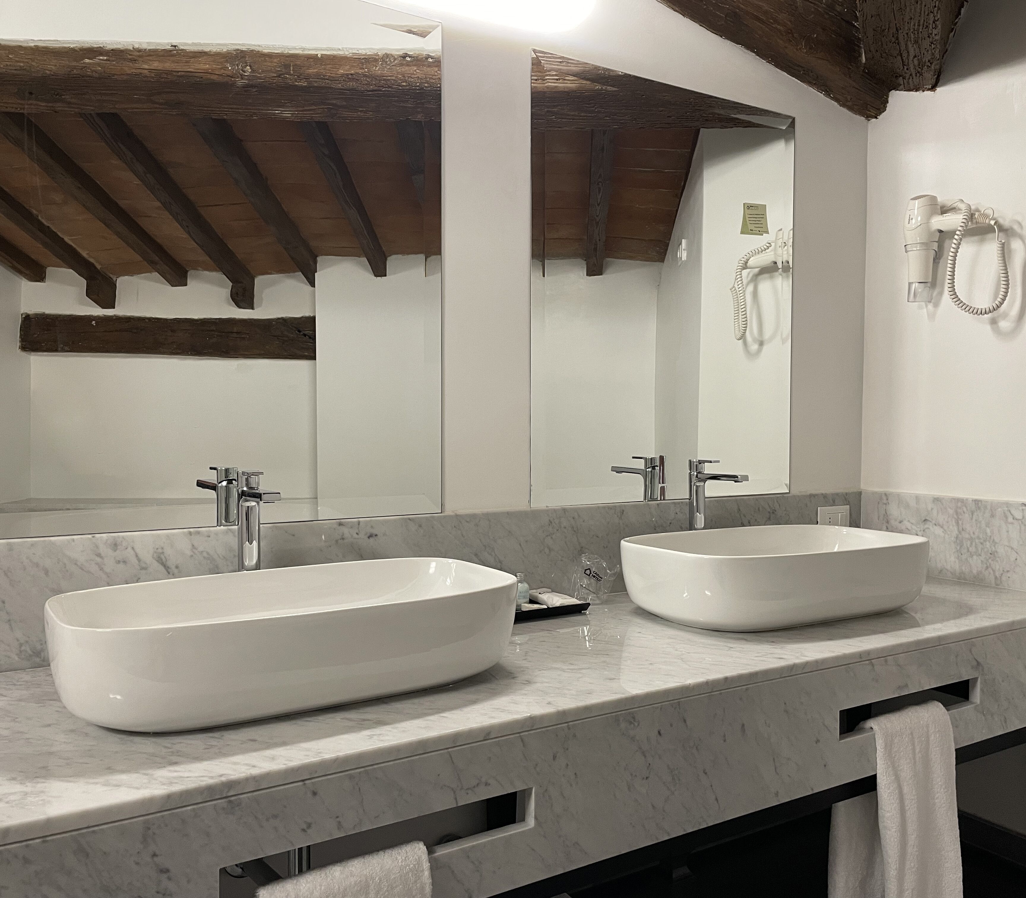 A bathroom with two large, white vessel sinks, a mirror, and a towel rack.