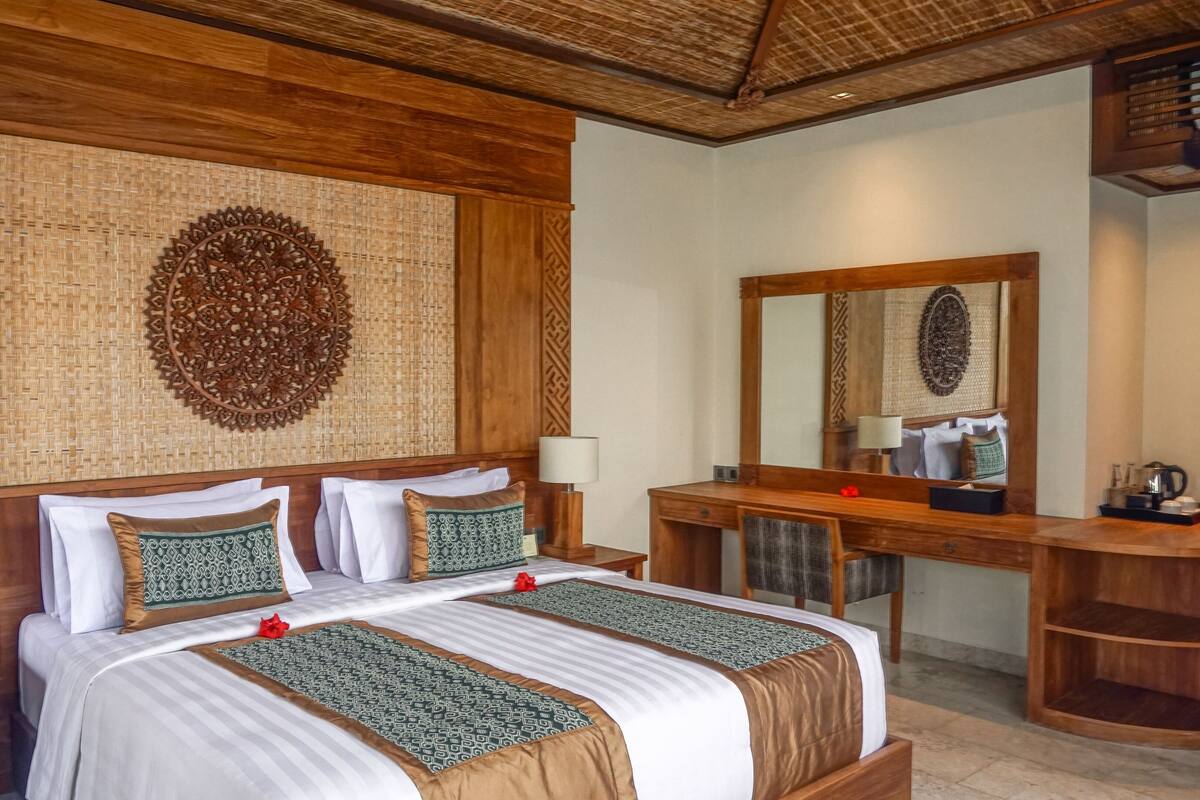 A hotel room with a large bed, two bedside tables, a wooden desk, and a mirror.
