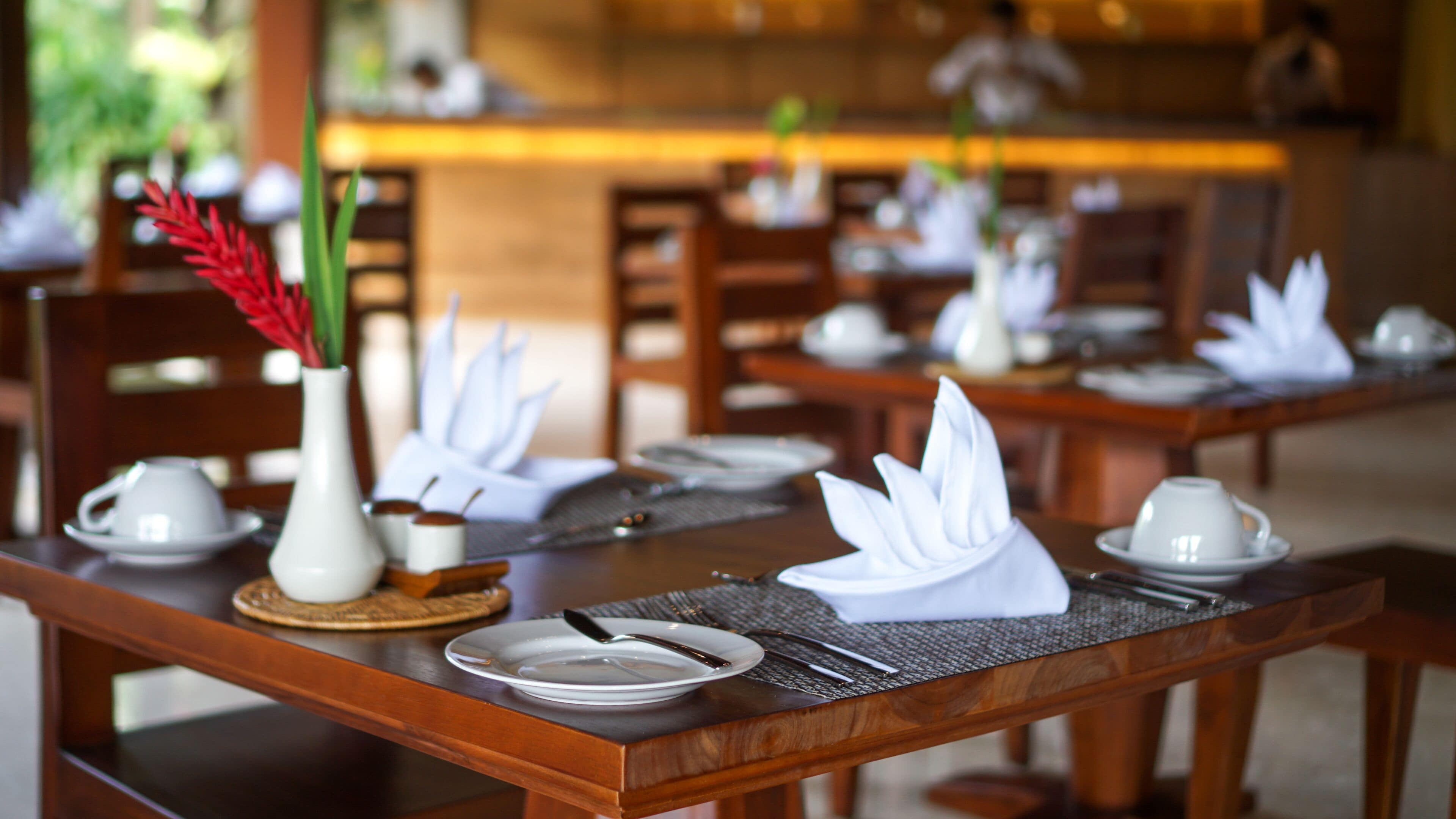 A dining table set with white plates, silverware, and a white napkin.