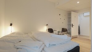 A modern hotel room with a large bed, a desk, and a chair. - Bankbox Hostel Aabybro (Aabybro)
