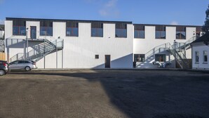 A modern building with a white facade, multiple windows, and a staircase leading to the entrance. - Bankbox Hostel Aabybro (Aabybro)