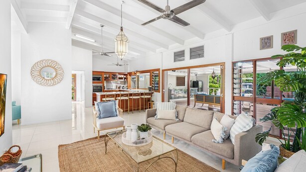 A spacious living area with a sofa, coffee table, and a view of the kitchen and balcony.