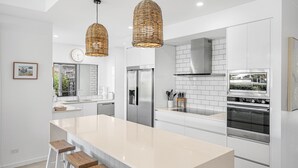 Une cuisine moderne dotée d’un îlot central, d’appareils électroménagers en acier inoxydable et d’une grande fenêtre.