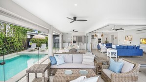 Un espace de vie moderne doté d’une piscine, d’un coin salon extérieur et d’un espace cuisine.