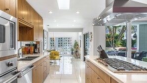 Una cocina moderna con electrodomésticos de acero inoxidable, armarios de madera y vistas a un patio exterior con piscina.