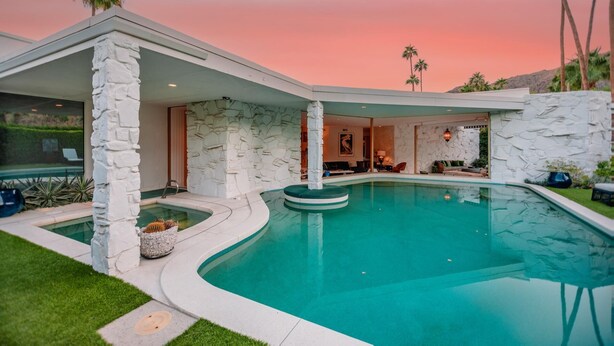 Une maison moderne dotée d’une piscine, de murs en pierre et d’un espace patio.