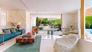 Un salon moderne avec un mur en pierre, un canapé bleu, une table basse et une vue sur une piscine.
