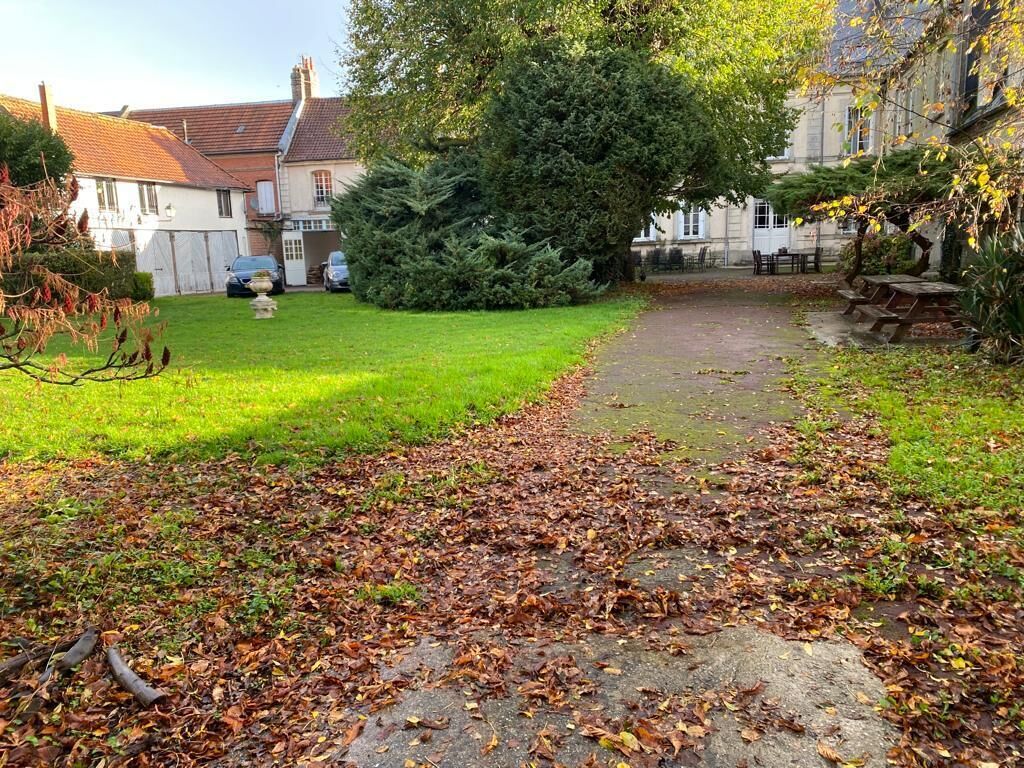 A courtyard with a stone pathway, a large tree, and a bench.