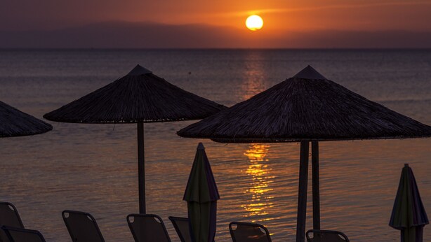 A sunset view with beach umbrellas and lounge chairs. - Eantos Studios and Suites (Thermaikos)