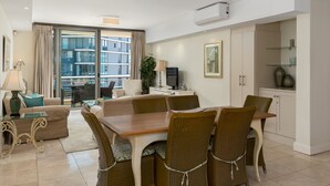 A modern living room with a dining area, large windows, and a view of the city. - Canal Quays 607 (Cape Town)