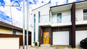 Ein modernes, zweistöckiges Haus mit Garage, kleinem Vorgarten und blauem Himmel.