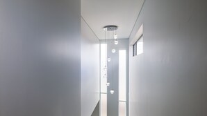 Ein modernes Interieur mit einem geraden Korridor, Pendelleuchten und großen Fenstern, die natürliches Licht hereinlassen.