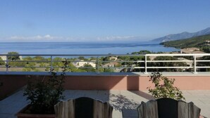 Un balcone con vista sul mare e montagne lontane.