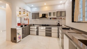 Une cuisine moderne dotée d’un îlot central, d’appareils électroménagers intégrés et de luminaires suspendus.