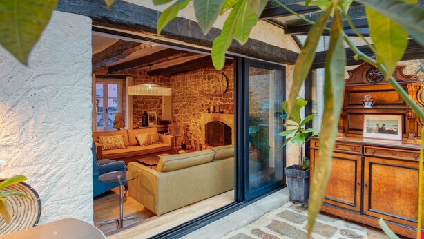 Una sala de estar acogedora con chimenea de piedra, asientos cómodos y vistas a través de un ventanal.