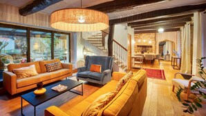 Una sala de estar moderna con sofá, sillón y mesa de centro. Se ve una escalera que sube a otra habitación.