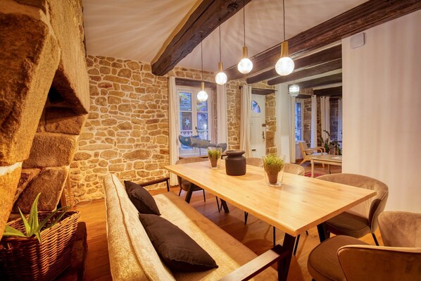 Um espaço de refeições acolhedor com mesa de madeira, bancos e luminárias pendentes.