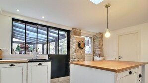 Una cocina moderna con un muro de acento de piedra, un ventanal grande y una encimera de madera.