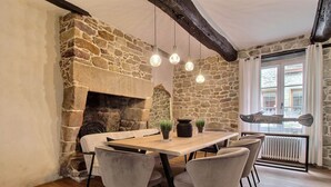 Un comedor rústico con chimenea de piedra, mesa de madera y lámparas colgantes.