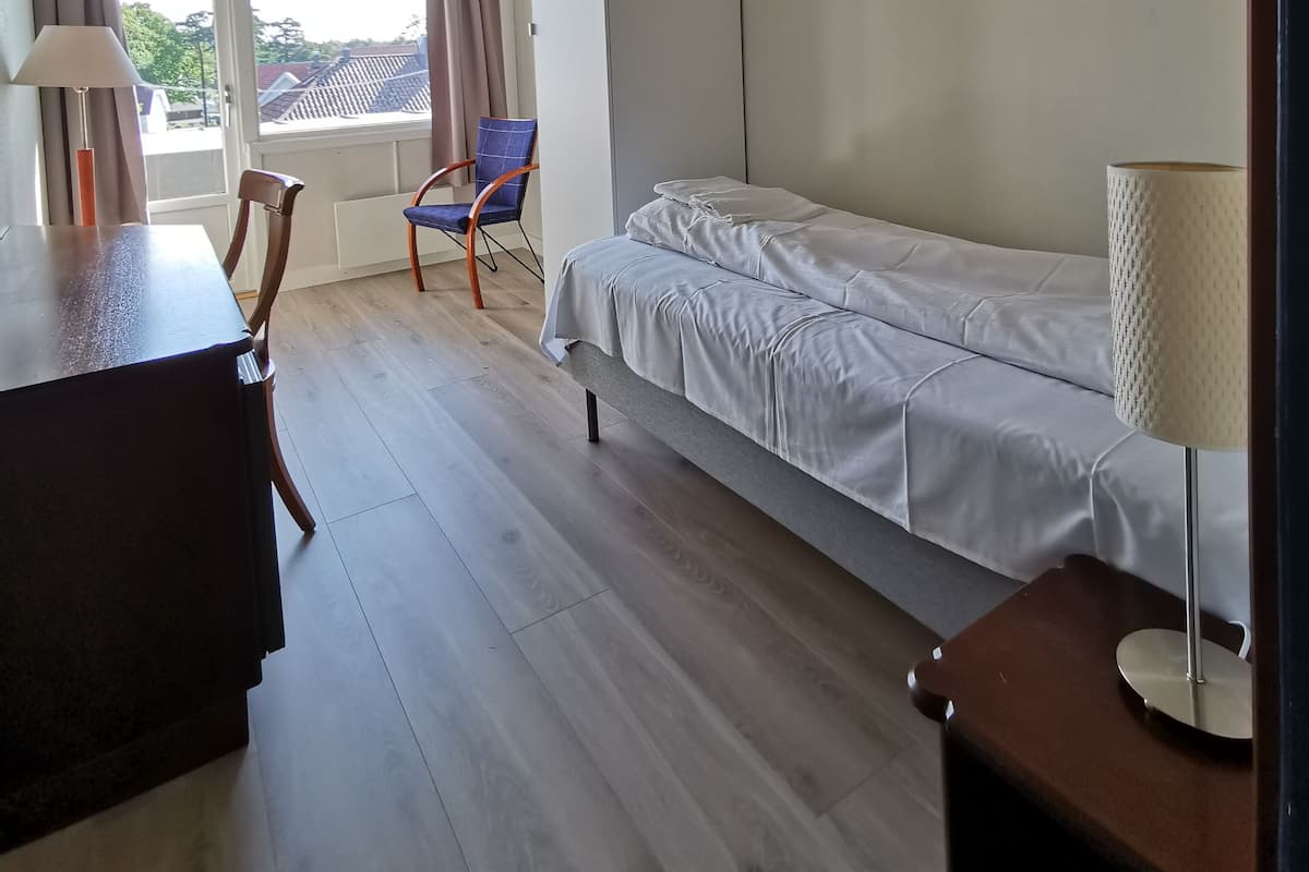 A hotel room with a bed, a desk, a chair, and a window with curtains.