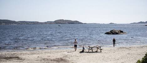 Une plage avec une table de pique-nique et des personnes près de l’eau.