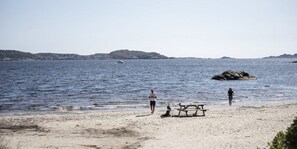 A beach with a picnic table and people near the water. - SKAP Hostel Mandal (Lindesnes)