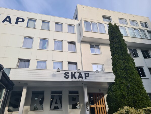 A building with a sign reading "SKAP Kreativ folkehøjskole" indicating a school. - SKAP Hostel Mandal (Lindesnes)