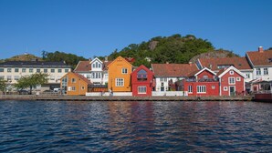 Una propiedad frente al mar con casas de colores, un muelle y una colina con árboles al fondo.