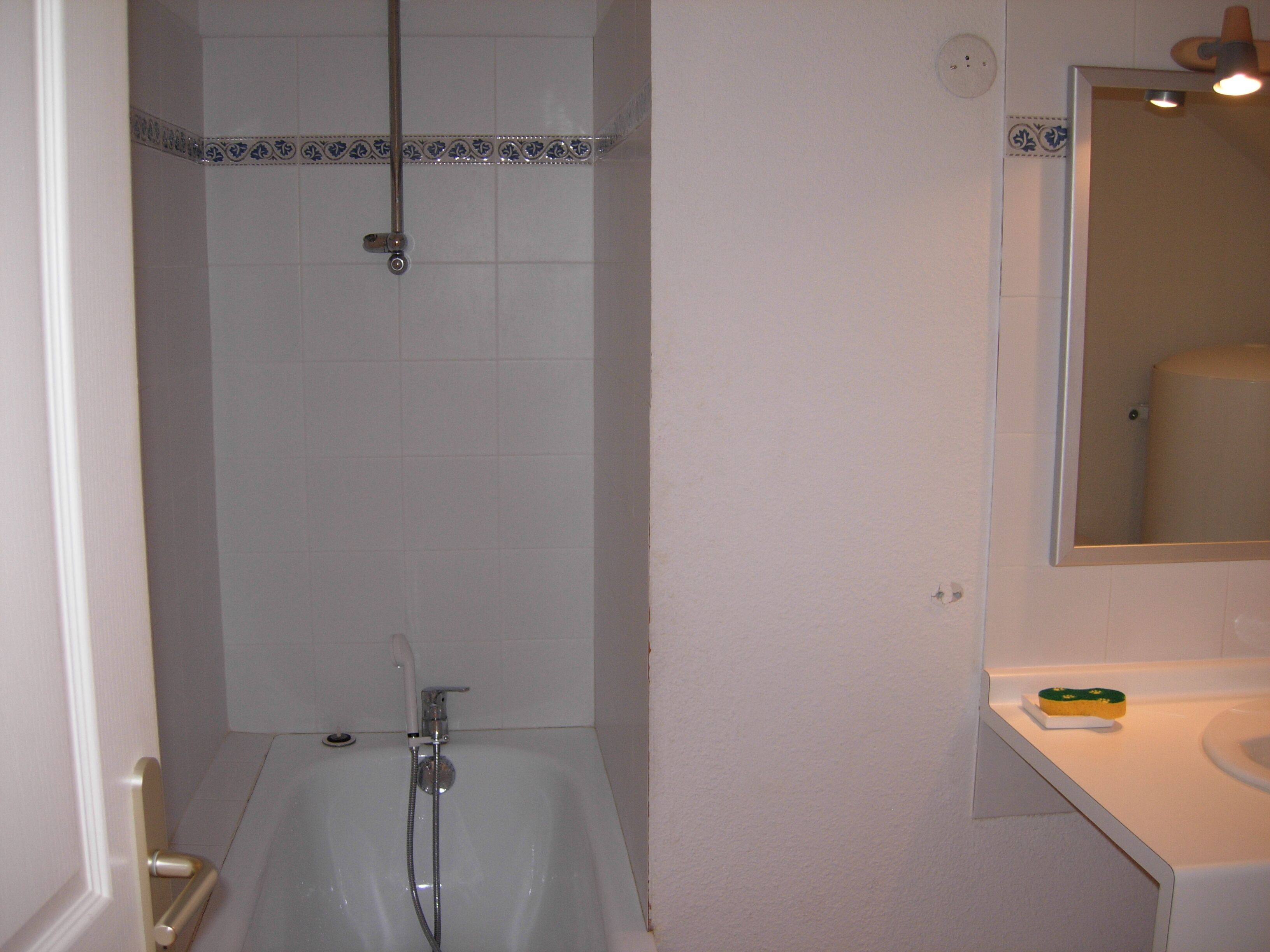 A bathroom with a bathtub, a shower, a toilet, and a mirror.