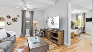 A modern living room with a sofa, coffee table, and a television. There are decorative plates on the wall and a ceiling fan.